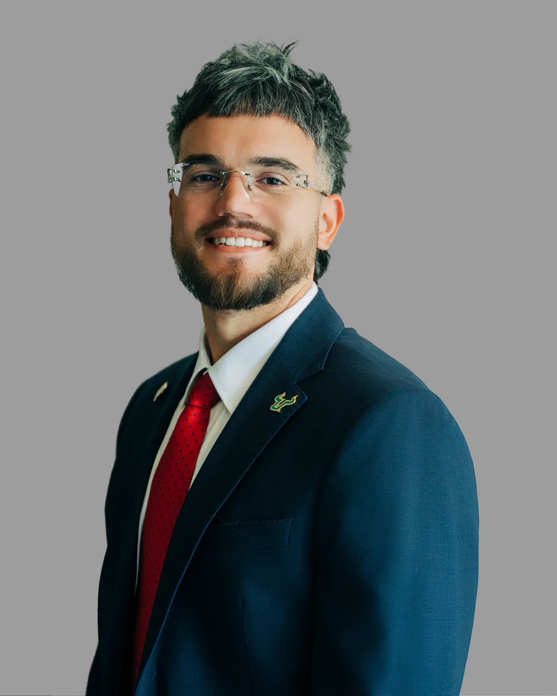 Studio portrait of Steven Lombard in a navy suit and red tie